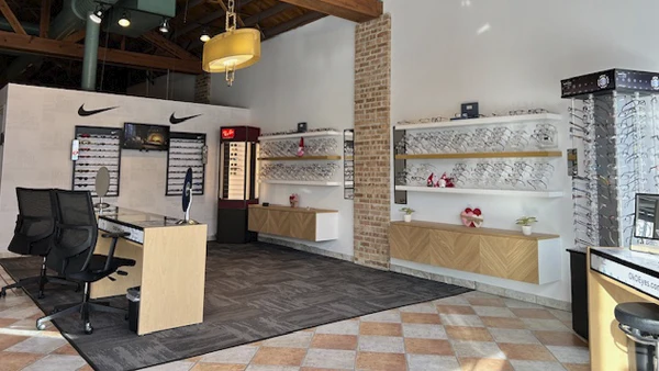 Modern eyewear store interior featuring display shelves, branded frames, and a clean, organized layout.
